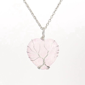Detailed wire-wrapped silver tree of life design on a heart-shaped pink quartz pendant