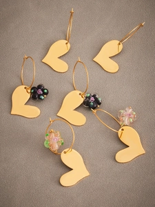 Détail de boucles d'oreilles cœur dorées avec fleurs en résine sur tissu gris texturé