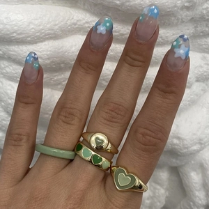 Hand wearing stacked green enamel heart rings in gold plated stainless steel