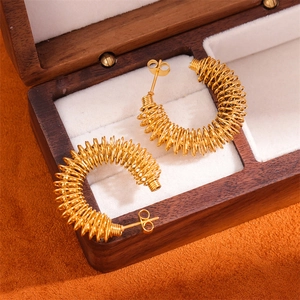 Detail of 18K gold-plated stainless steel twisted hoop earrings in a wooden jewelry box