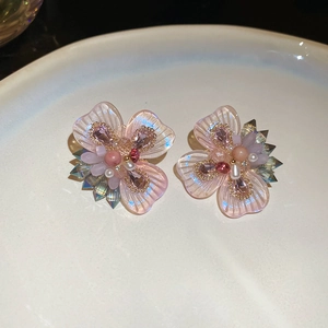 Close-up of pink crystal flower stud earrings with resin petals and faux pearls