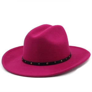 Detail of rose red felt cowboy hat featuring a black leather band with gold metal studs