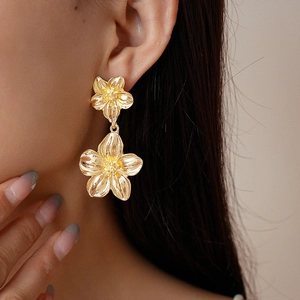 Close-up of elegant gold flower drop earrings featuring dual-layered metallic petals
