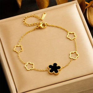 Close-up of gold stainless steel bracelet with black flower pendants on a jewelry box