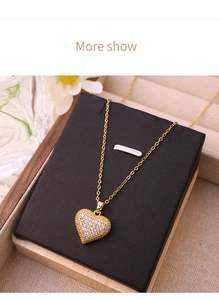 Close-up of gold heart pendant with pavé cubic zirconia and fine chain on black pad