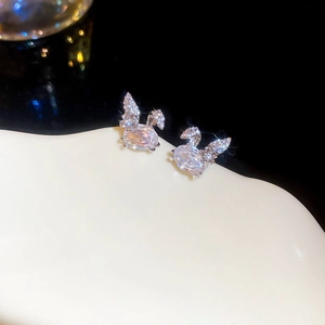 Macro shot of silver rabbit earrings with zircon inlay on a white textured surface