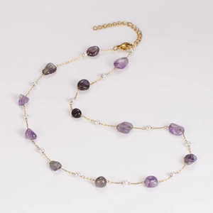 Detailed close-up of gold chain necklace with purple irregular stones and white beads