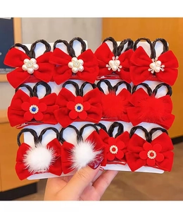 Detail of red children's bow hair clip with pearls, fur balls, and cute synthetic hair braid