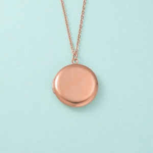 Détail du collier médaillon rond en or rose avec une finition en métal brossé texturé