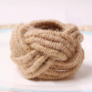 Handwoven natural jute napkin ring with circular braided knot design on a white ceramic plate