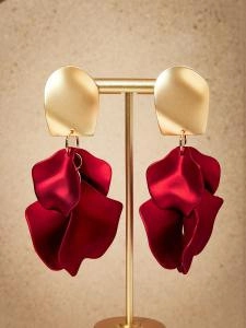Détail de boucles d'oreilles à pompon rouge avec motif de pétales sur un présentoir à bijoux