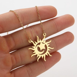 Detailed macro shot of a gold sweater necklace with hollow sun, moon and star charms