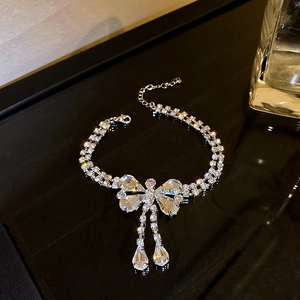 Gros plan détaillé d'un bracelet nœud argenté orné de strass sur fond noir brillant