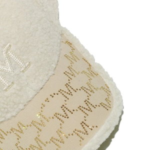Macro detail of plush lamb wool baseball cap with crystal-studded M logo pattern