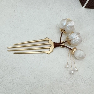 Détail de l'épingle à cheveux dorée avec fleurs de magnolia blanc et pompon perlé