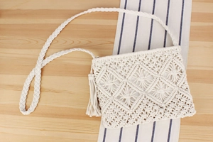 Detailed close-up of handmade white cotton woven shoulder bag with boho tassel accents