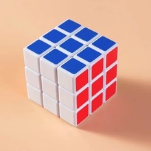 Close-up of a 3x3 speed cube puzzle with blue, red, and white faces on pink background