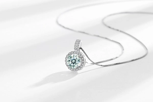 Macro shot of silver Moissanite pendant with a round main stone and halo diamond setting