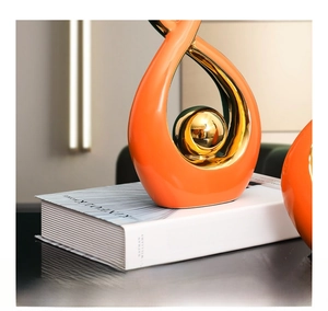 Close-up of orange teardrop ceramic ornament with a golden metallic electroplated sphere