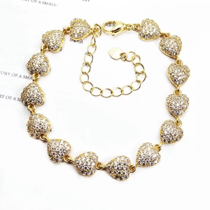 Detailed view of heart-shaped gold bracelet with micro-pave zircons and lobster clasp