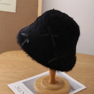 Detail of plush black bucket hat featuring soft faux fur texture and elegant ribbon bows