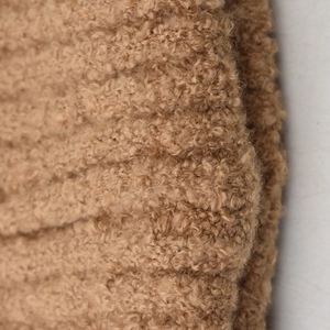 Macro shot of light brown fluffy fleece knit beanie fabric showing soft plush texture