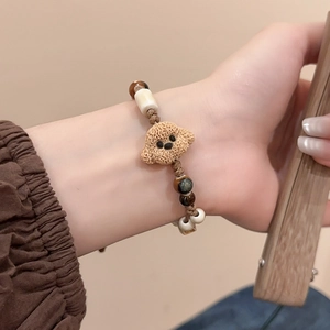 Detailed view of handmade woven bracelet with cute brown puppy bead and cat-eye stones