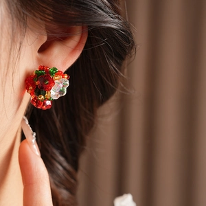 Close-up of vintage beaded flower earring in red and green worn by a fashion model