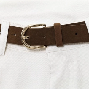 Women's dark brown matte leather belt with gold D-buckle on white wide-leg jeans