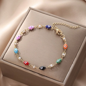 Macro detail of gold Hamsa Hand bracelet with colorful evil eye charms and pearls