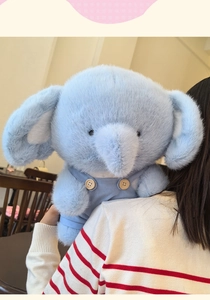 Detailed view of the soft light blue plush elephant doll wearing blue textured overalls