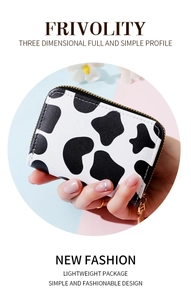 Close-up of portable PU leather card holder with black and white cow print and gold zipper