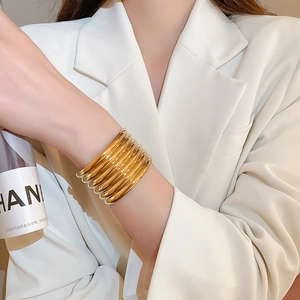 Macro view of stacked thick golden stainless steel bangles with polished metallic texture
