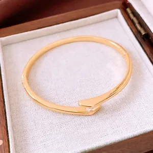 Gold-plated metal bangle with cubic zirconia displayed in a wooden jewelry box