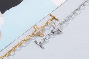 Detail of vintage OT clasp chain bracelets with crystal-set cross charms in gold and silver