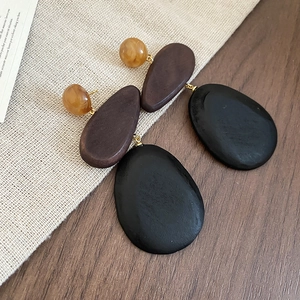 Detailed close-up of retro wooden and resin drop earrings on a rustic linen background