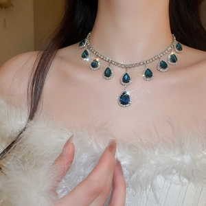 Close-up of royal style necklace with blue water-drop crystals on a female model