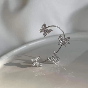 Sparkling silver butterfly ear cuff with rhinestones on a white ceramic plate
