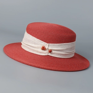 Detail of red straw sun hat with creamy chiffon ribbon and brown resin stone beads