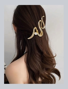 Detailed view of a golden wave hair claw clip with pearl accent on long hair