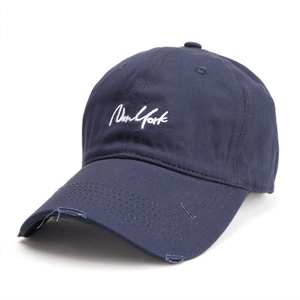 Close-up of New York embroidery on distressed navy blue cotton baseball cap with torn brim