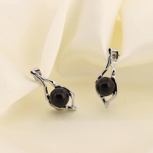 Detail of silver irregular metal earrings featuring a round black pearl on silk fabric