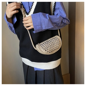 Close-up of beige moon-shaped bag featuring silver studs and woven knot strap details