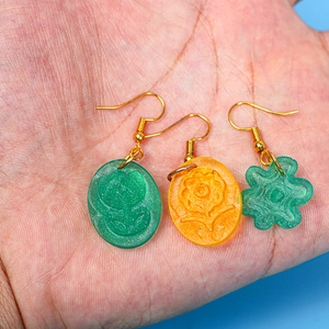 Primer plano de pendientes florales de resina hechos a mano con ganchos dorados