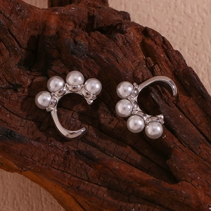 Gros plan de boucles d'oreilles argentées en C avec cinq perles blanches sur bois