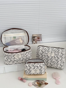 Dettaglio di tre beauty case in velluto a coste floreale con tasche a rete e zip