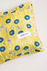 Macro shot of jacquard fabric cosmetic bag with large yellow flowers and H&R BAG logo