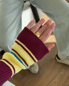 Close-up of wide matte brushed gold ring paired with vintage striped knit sleeve detail