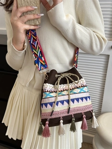 Woven straw bucket bag with ethnic embroidery, fringe tassels and wide geometric strap