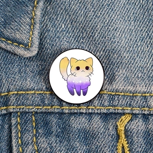 Round enamel cat brooch with rainbow gradients pinned on blue denim jacket fabric